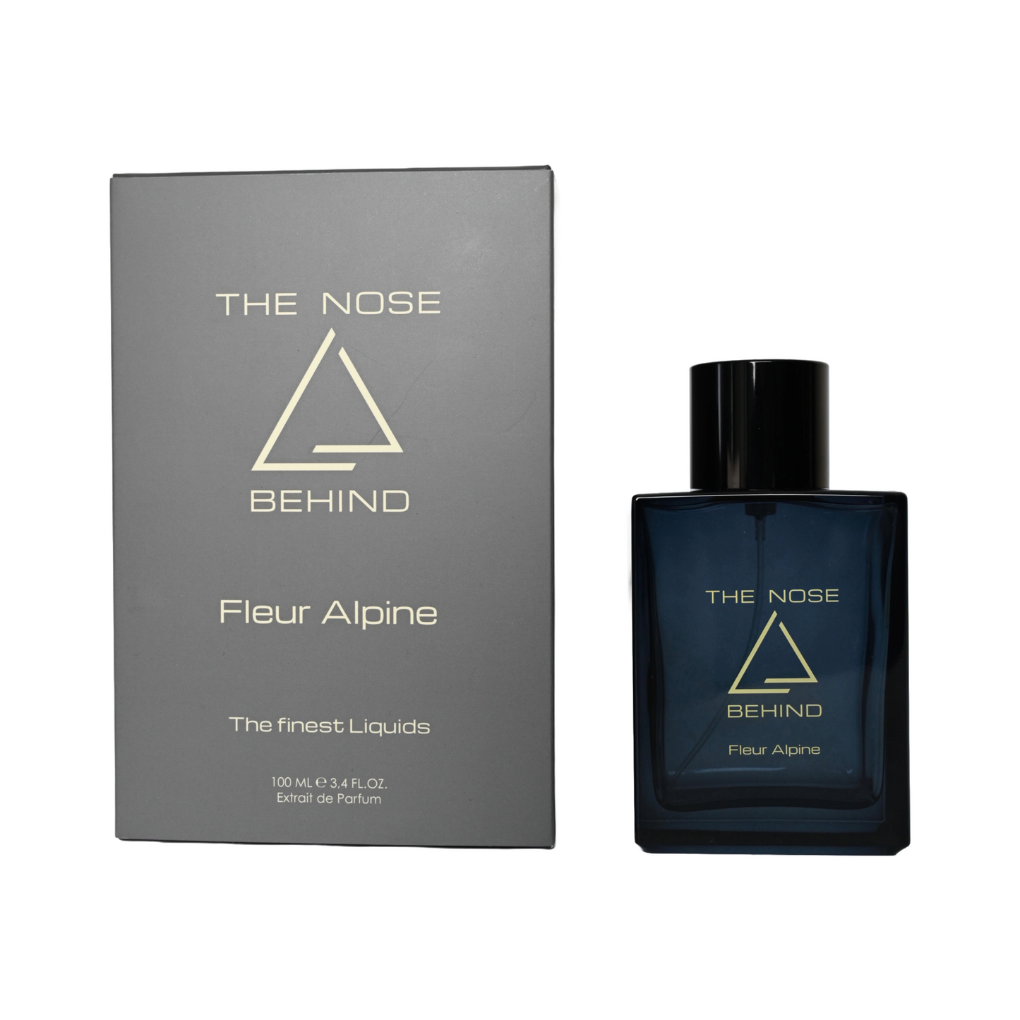 Parfümflasche und Verpackung der Marke "The Nose Behind" mit dem Duftnamen "Fleur Alpine". Die dunkelblaue Flasche mit schwarzem Deckel zeigt ein minimalistisches, dreieckiges Logo und goldene Schrift. Die graue Verpackung trägt dasselbe Logo sowie die Aufschrift „Fleur Alpine“ und „The finest Liquids“. Unten steht: „100 ML e 3.4 FL.OZ. Extrait de Parfum“.